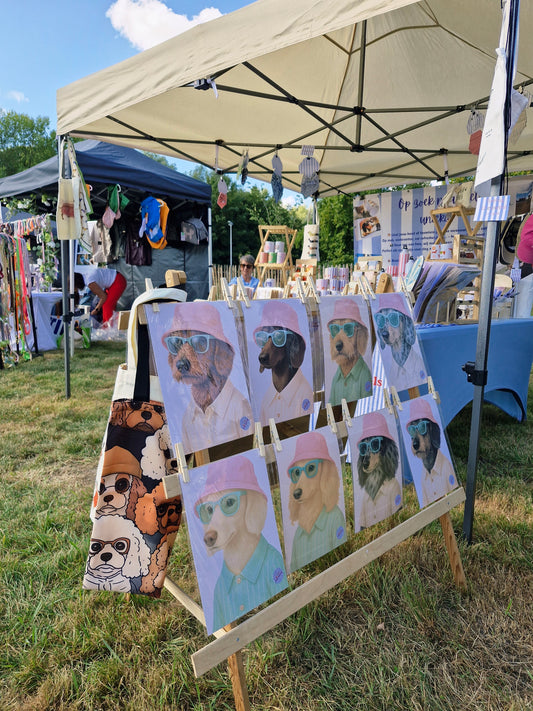 zicht met verschillende prints met teckels met roze zonnehoedjes op die te koop zijn op een hondenfestival