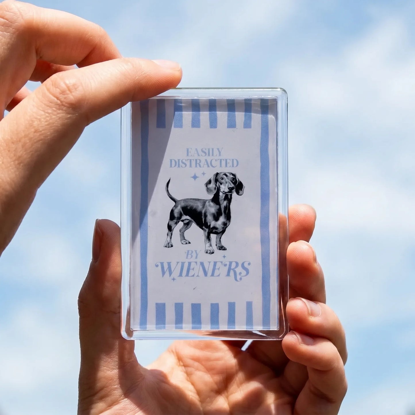 Acryl koelkastmagneet 'Easily distracted by wieners' met teckel illustratie – lichtblauwe tekst op wit, 7,7x5cm