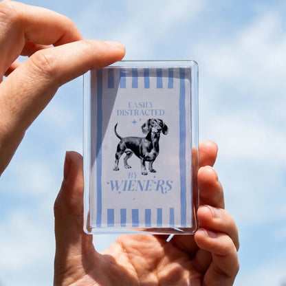 Acryl koelkastmagneet 'Easily distracted by wieners' met teckel illustratie – lichtblauwe tekst op wit, 7,7x5cm