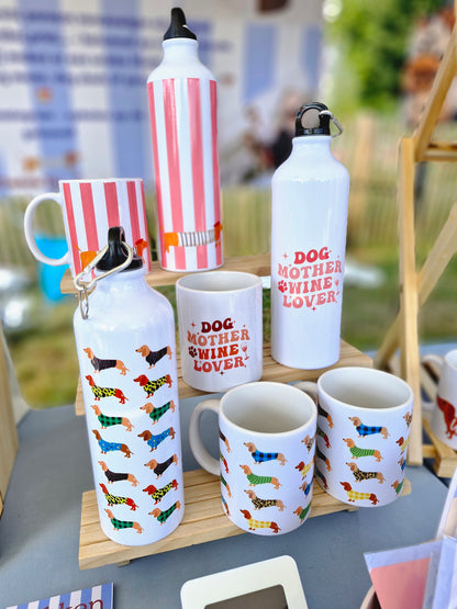 beeld van op een dog markt met waterflessen en mokken waar er een reeks van is: verschillende teckels, dog mother wine lover en de la saucisse parisienne zalmroze strepen met een teckel parijse stijl