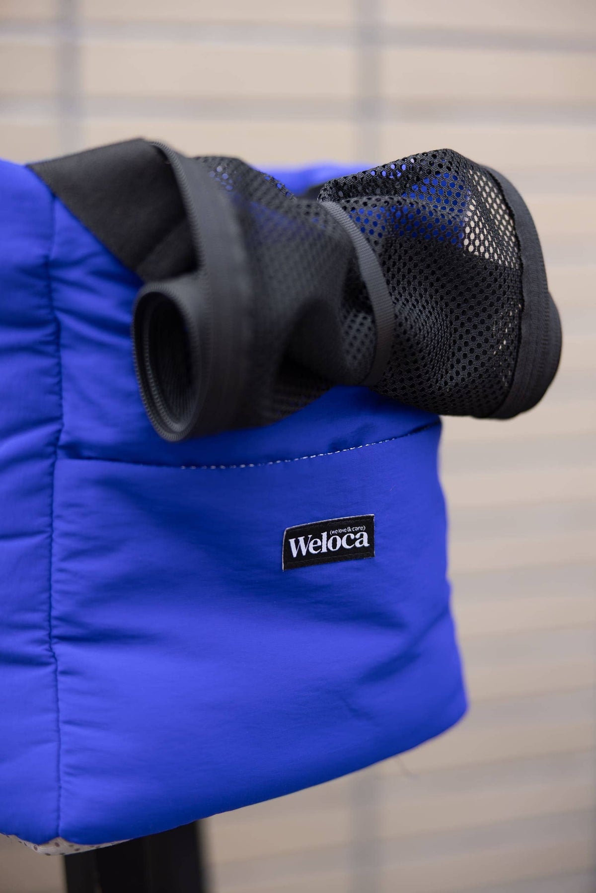 Opgerold gaas bovenaan de blauwe hondentas met Weloca-label