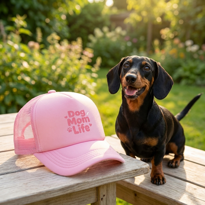 Roze trucker cap 'Dog Mom Life' op tafel naast teckel in de tuin