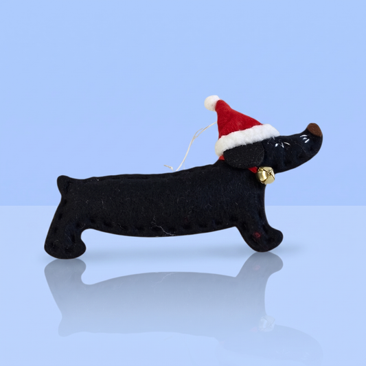 Zwart vilten teckel kerstornament met kerstmuts op blauwe achtergrond, voor teckelliefhebbers