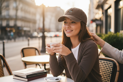 vrouw die op een terrasje zit, ze draagt een donkerbruine pet met de tekst oui-ner