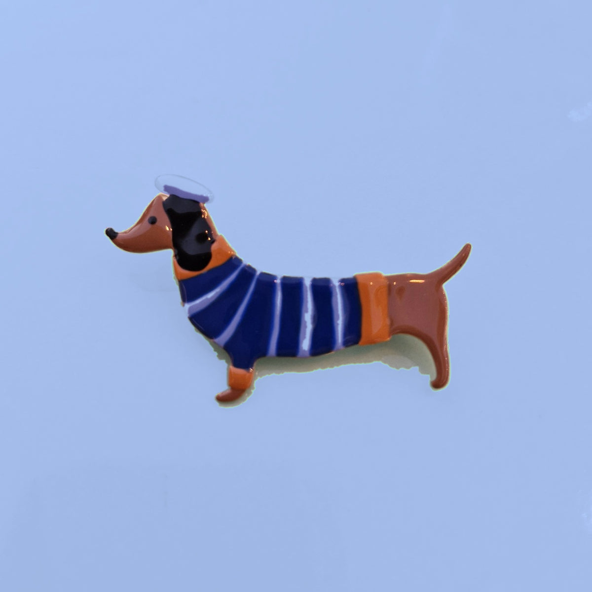 Emaille teckel broche met blauw gestreept truitje en lila baret