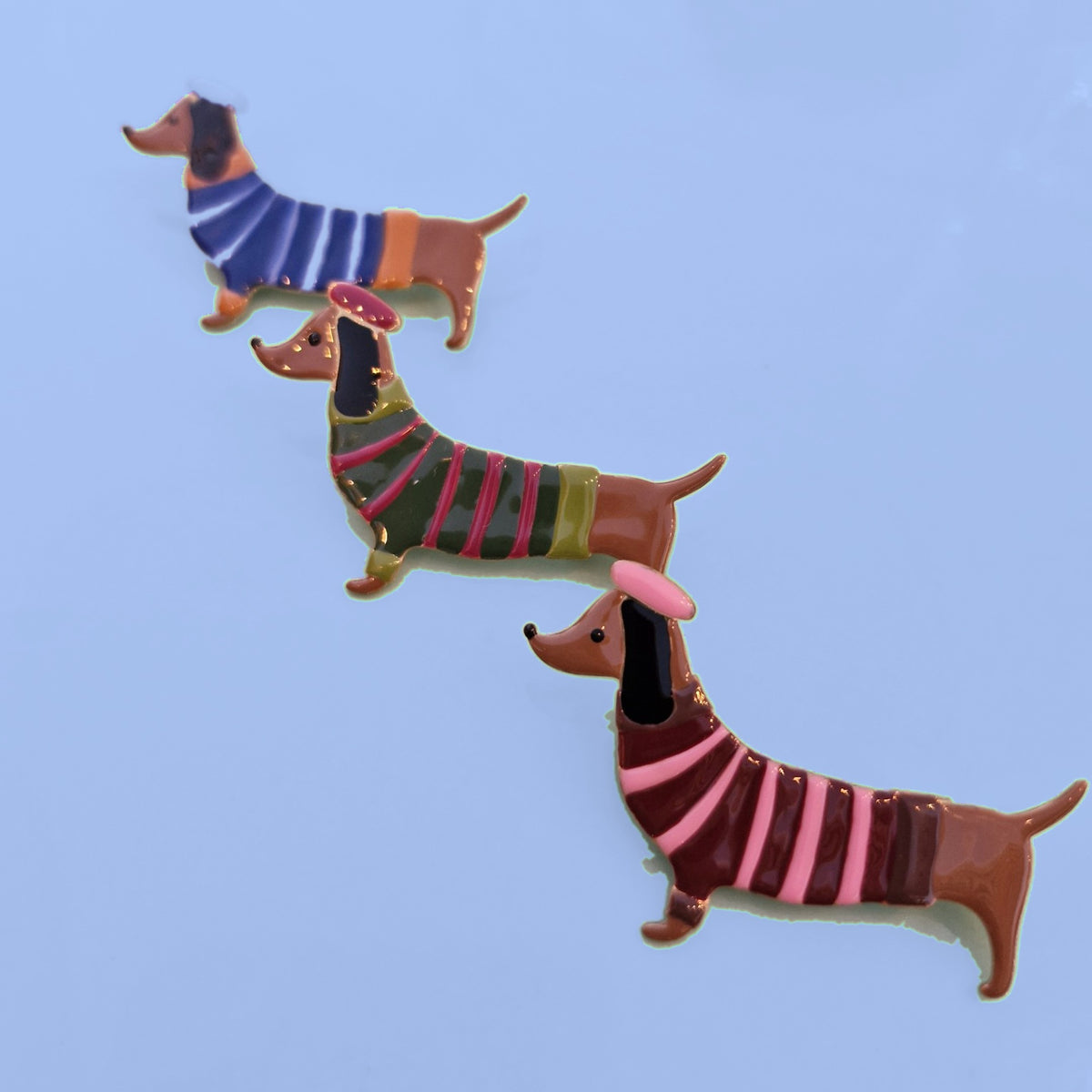 Drie teckel broches met gestreepte truitjes en baretjes