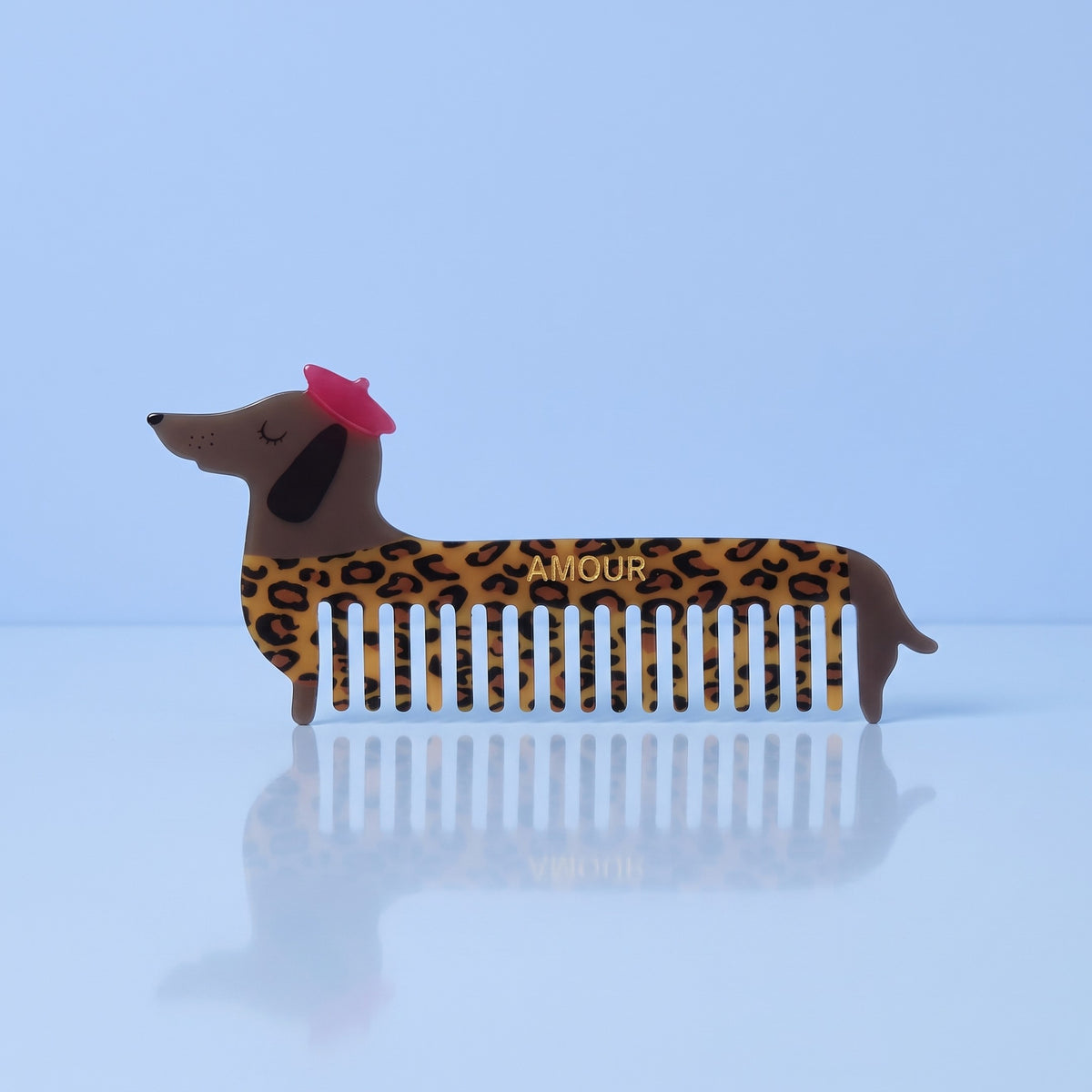 Teckel haarkam met luipaardprint, roze baret en gouden AMOUR op lichtblauwe achtergrond